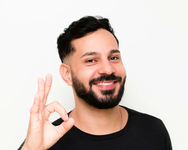 Thiago Heoli, de camiseta preta, sorrindo e fazendo sinal de OK